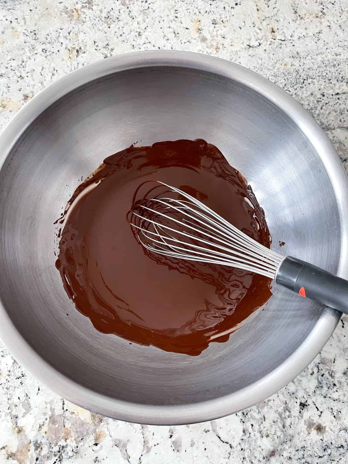 Whisking cocoa powder with hot water in mixing bowl.