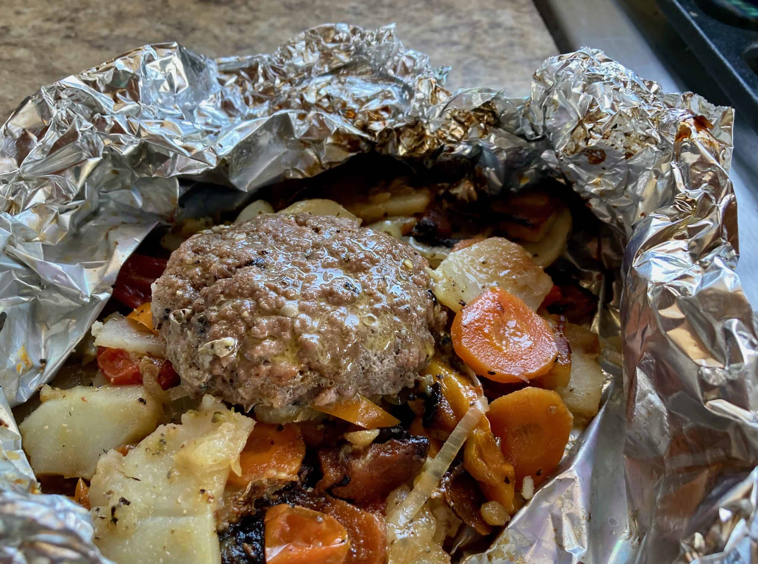 Hamburger and vegetables cooked in foil packet, open and ready to eat.