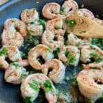 Shrimp with garlic butter wine sauce garnished with parsley in large nonstick skillet up close