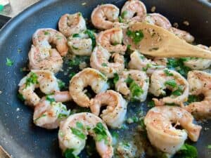 Shrimp with garlic butter wine sauce garnished with parsley in large nonstick skillet up close