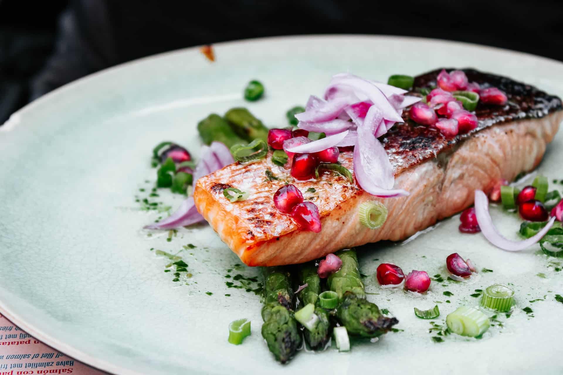 Salmon fillet with colorful vegetable garnishes on a white plate