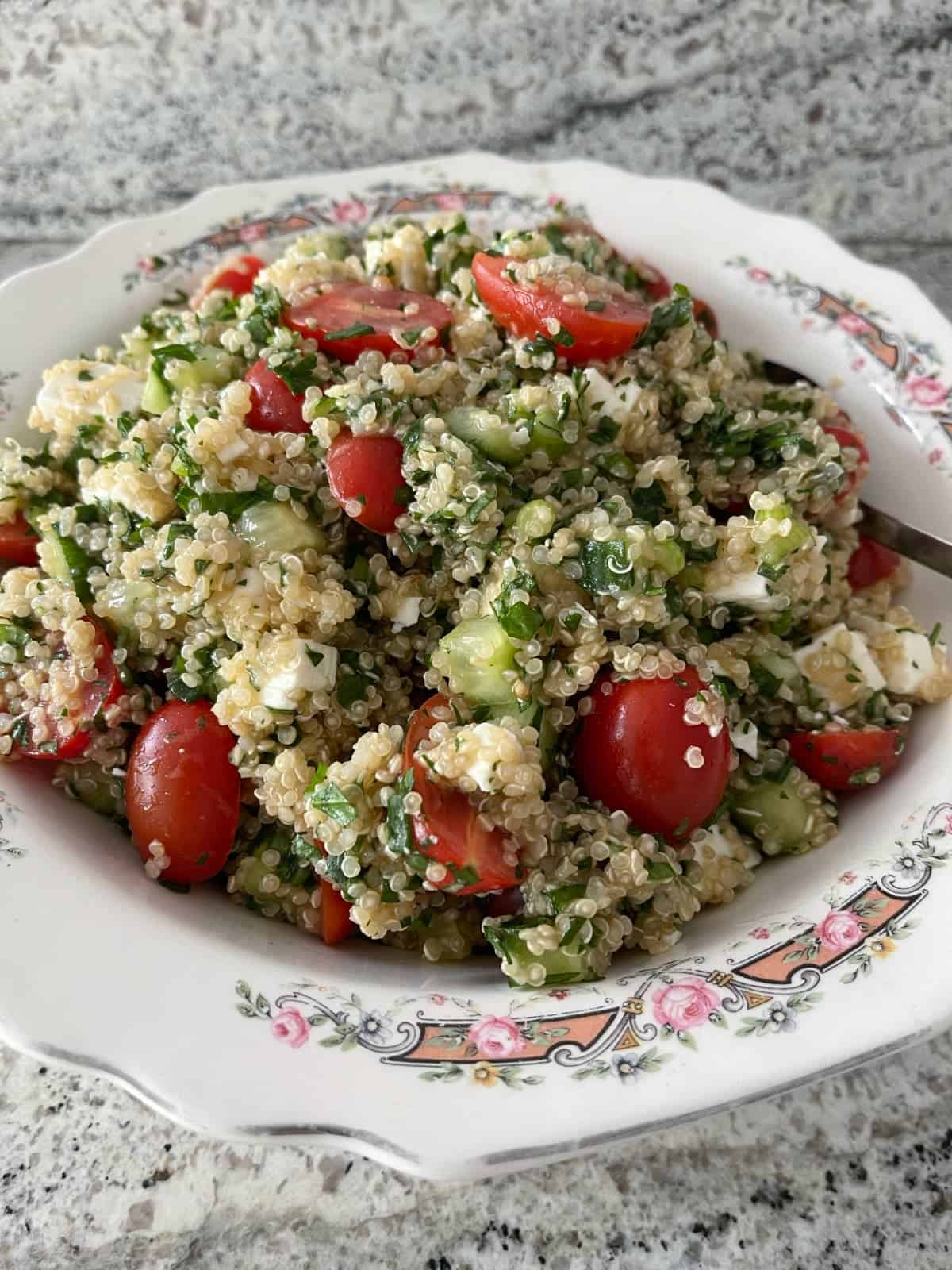 Quinoa Tabbouleh Feta Salad in white bowl with serving spoon.