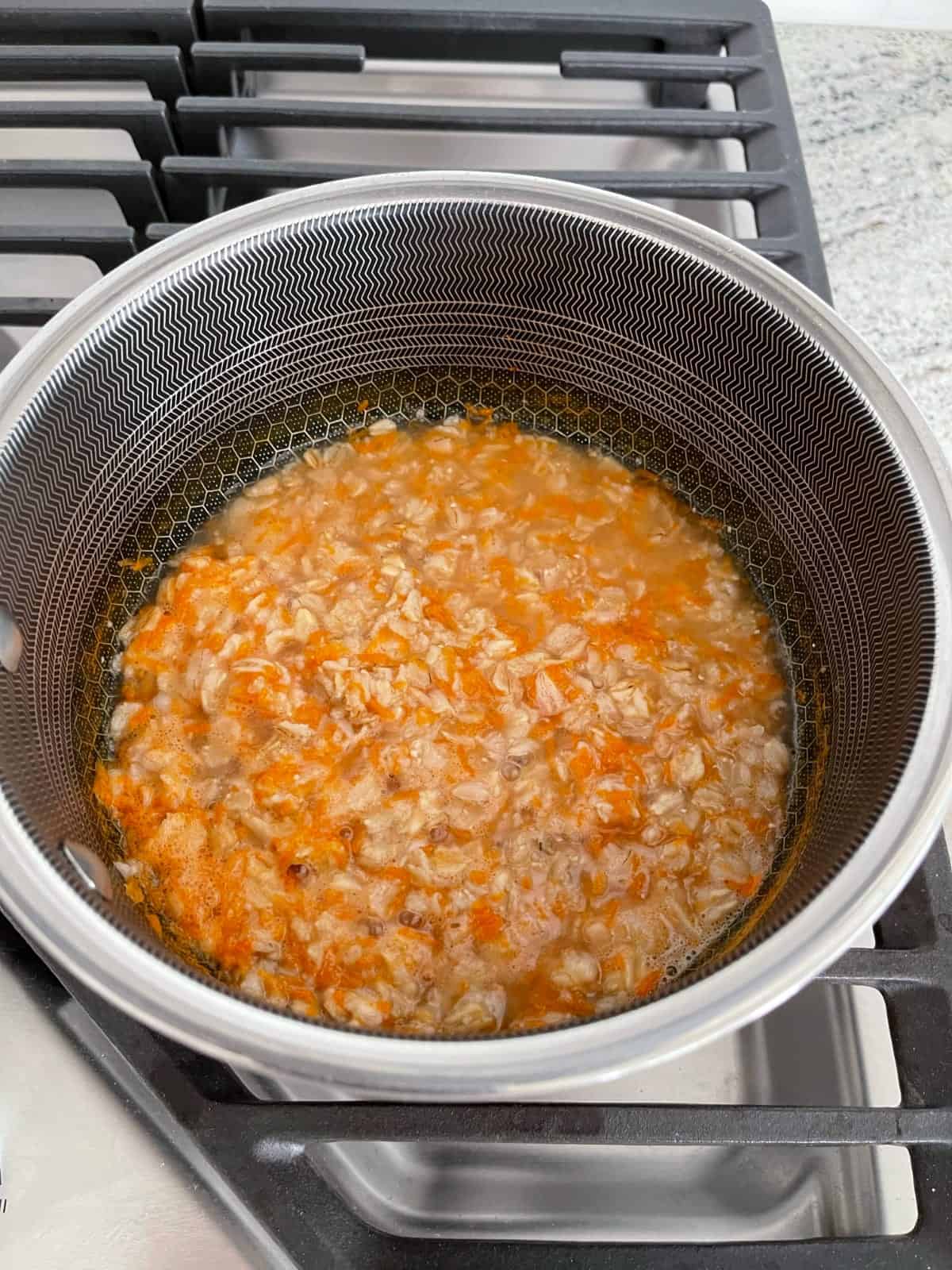 Simmering carrots, oatmeal and brown sugar in saucepan.