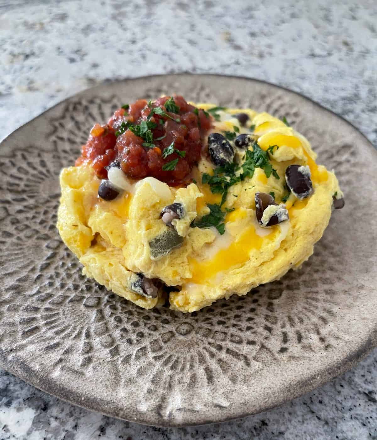 Tex Mex Eggs on small plate topped with fresh salsa and chopped cilantro.