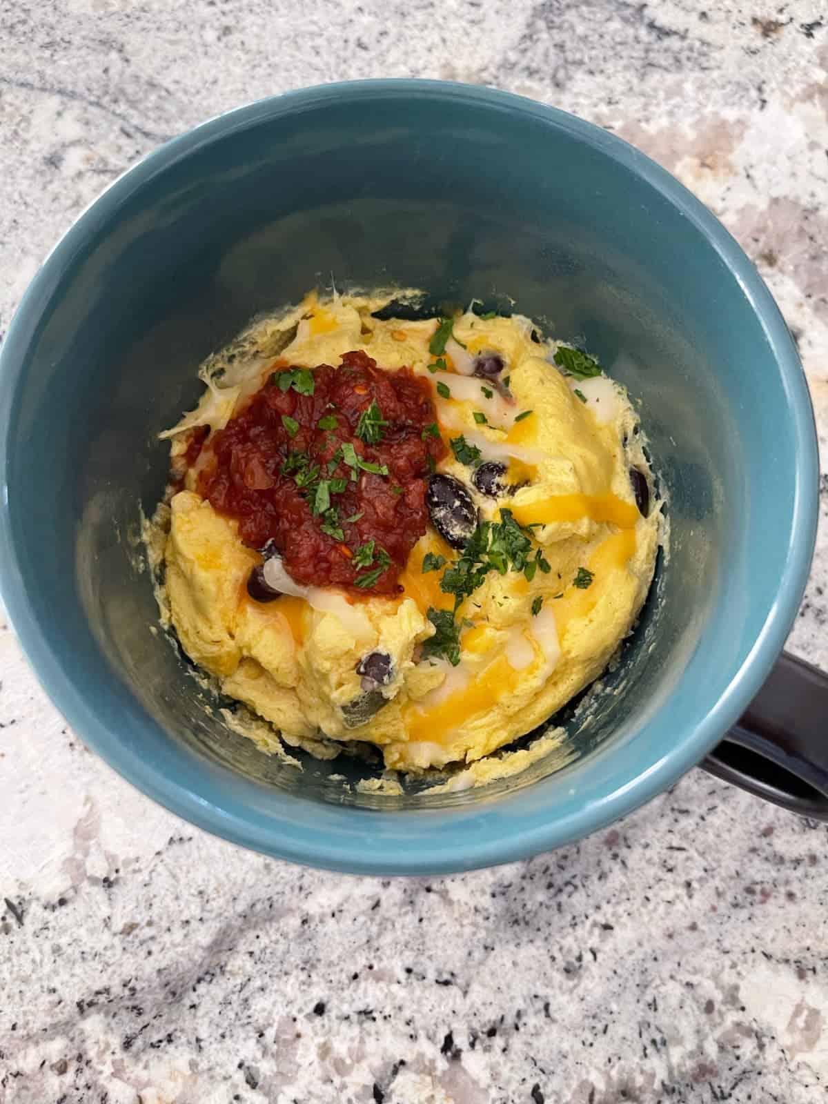 Tex Mex Egg Mug topped with salsa and chopped cilantro in mug.