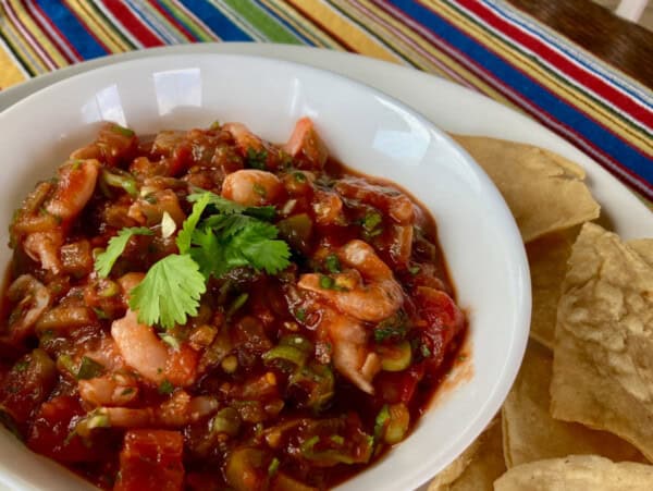 Shrimp Salsa Garnished with Cilantro White Bowl Surrounded by Tortilla Chips on Colorful Striped Mat