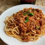 Slow Cooker Turkey Bolognese Over Spaghetti on White Plate Garnished with Parsley