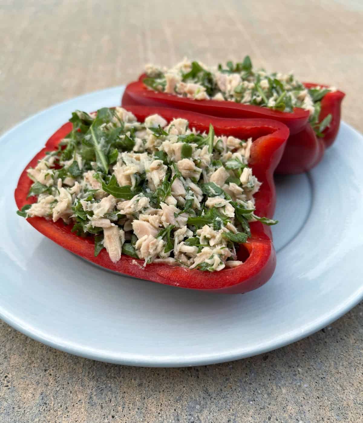 Herbed tuna stuffed red bell peppers on blue plate.