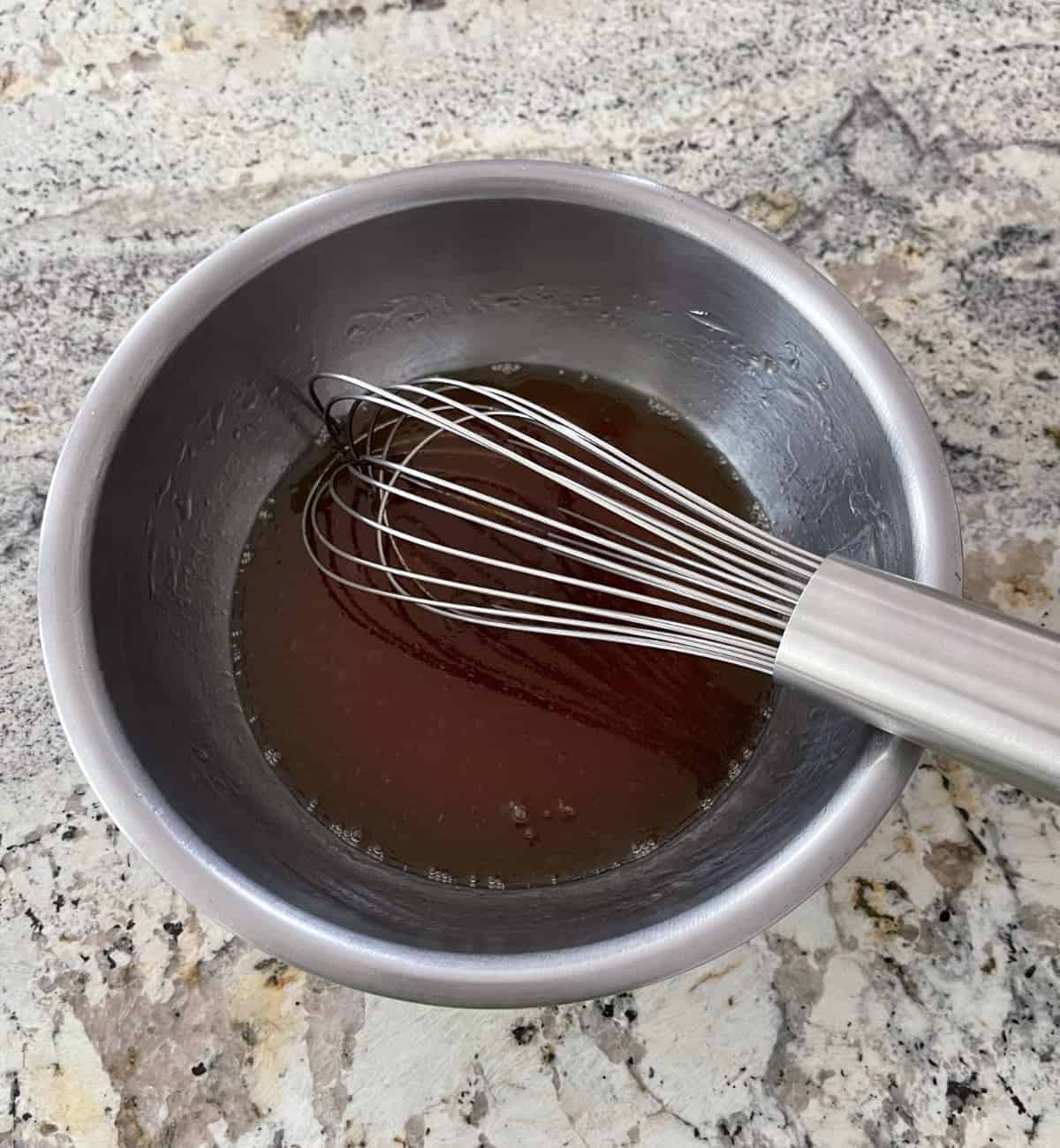 Whisking apple juice, brown rice syrup, oil and vanilla in mixing bowl.