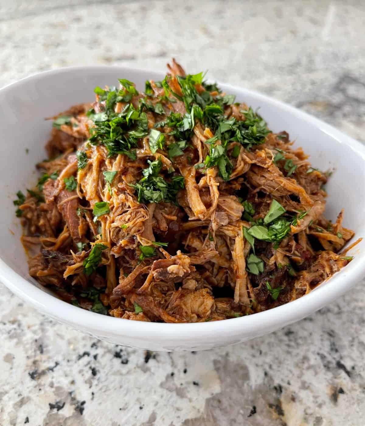 Cherry Chipotle Pulled Pork garnished with chopped cilantro in white serving bowl.