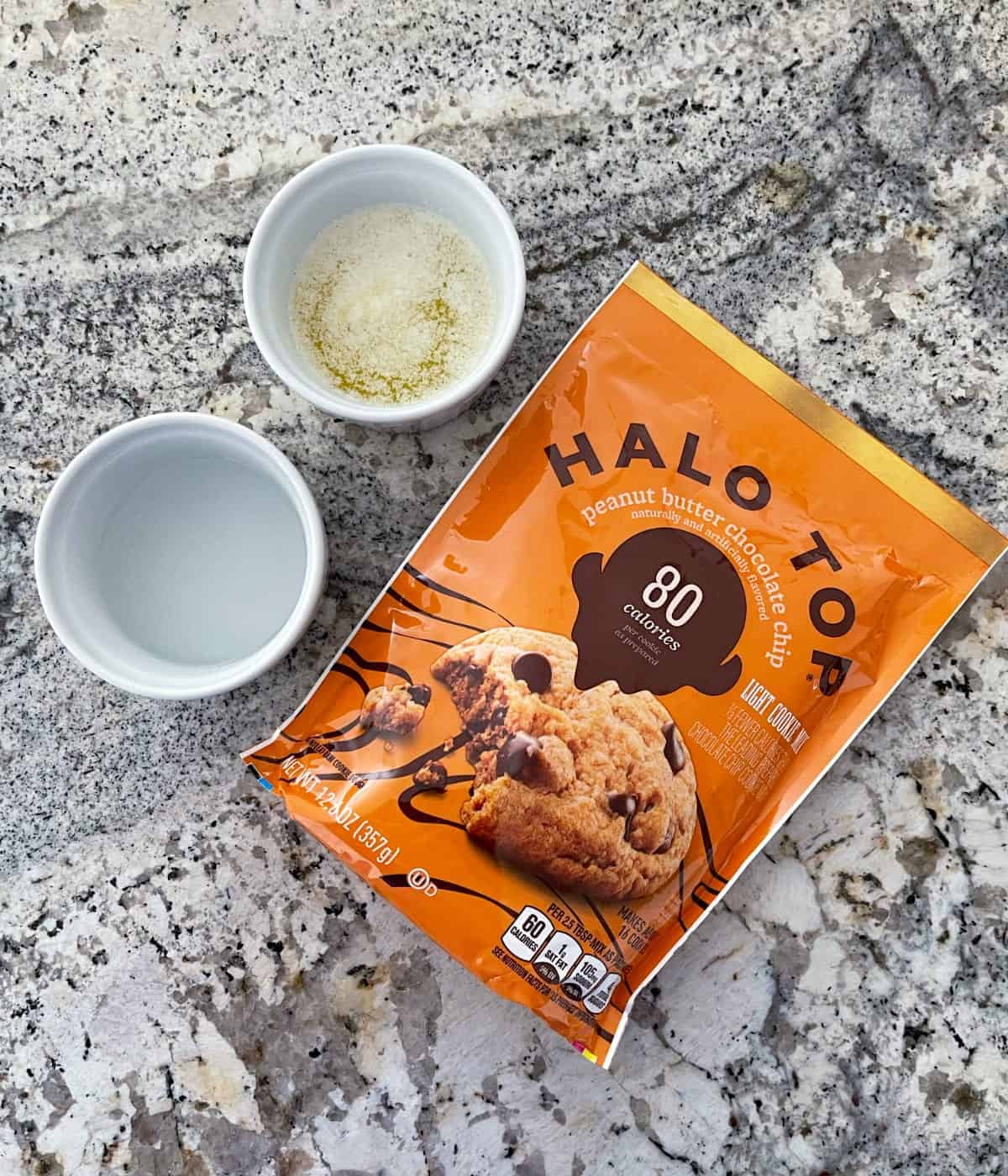 Package of Halo Top Peanut Butter Chocolate Chip Light Cookie Mix, a small ramekin of melted butter and small ramekin of water.