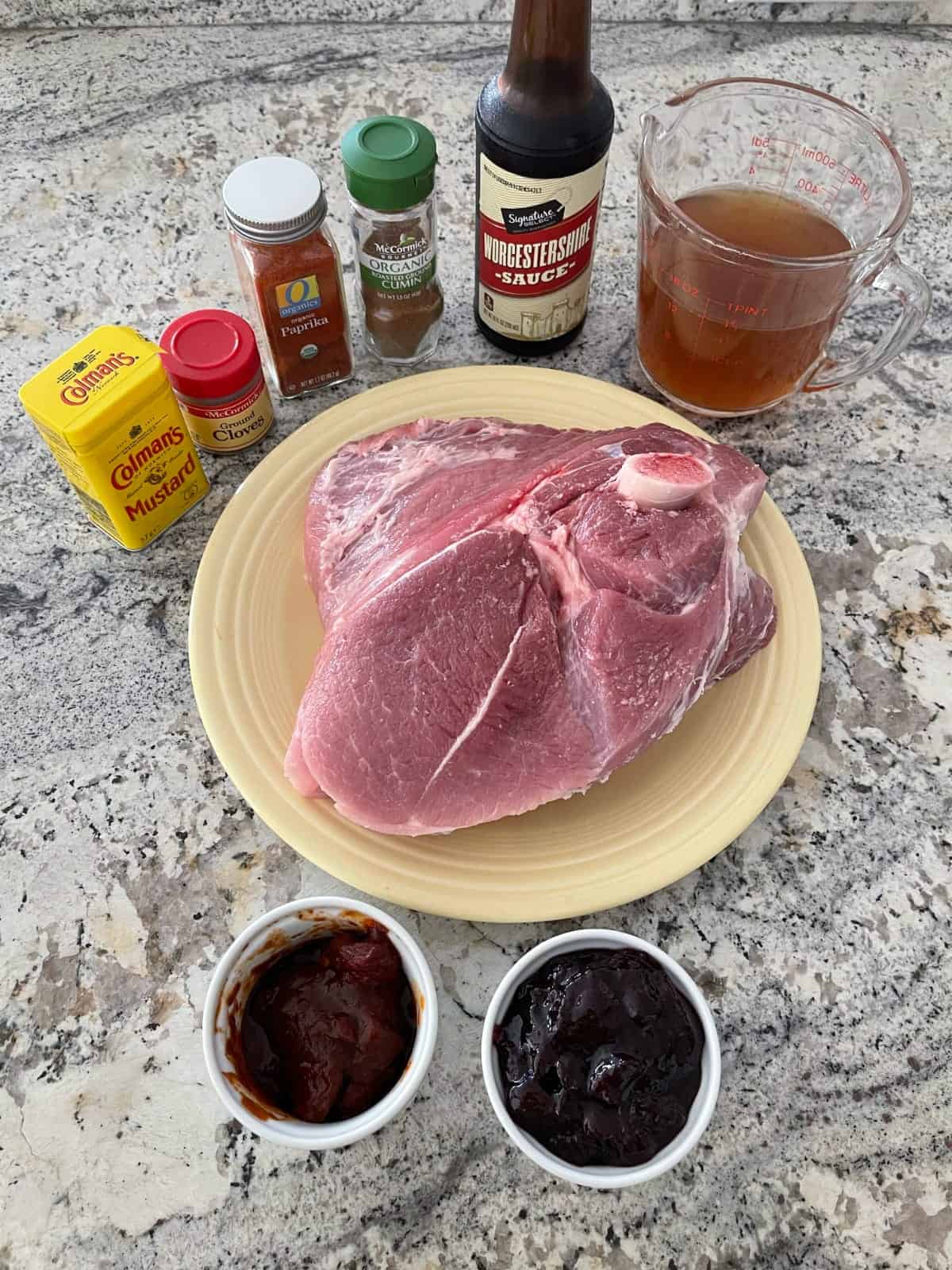 Ingredients for making Cherry Chipotle Pulled Pork including pork shoulder, cherry jam, chipotle peppers, chicken broth, Worcestershire sauce, cumin, paprika, cloves and dried mustard.