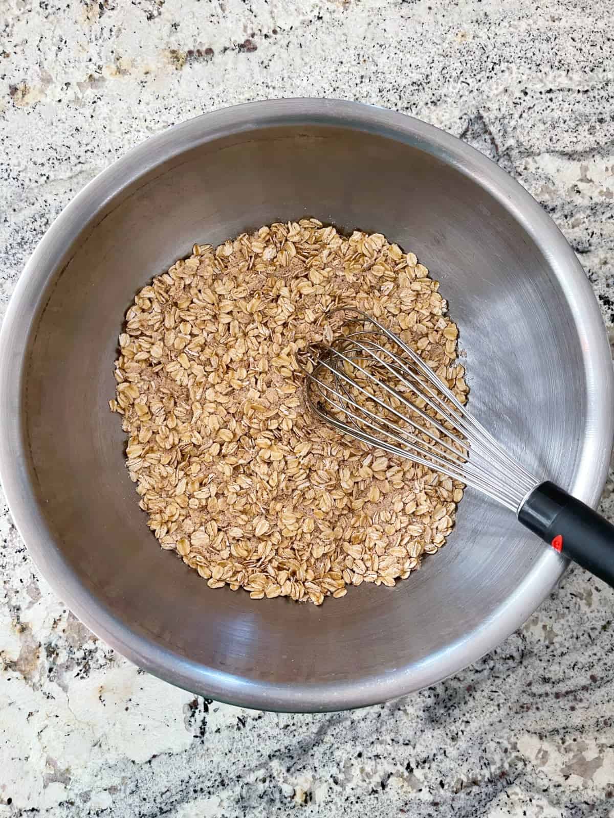 Rolled oats, almond flour, Truvia baking blend, ground nutmeg, cinnamon, baking soda and baking powder in mixing bowl with whisk.