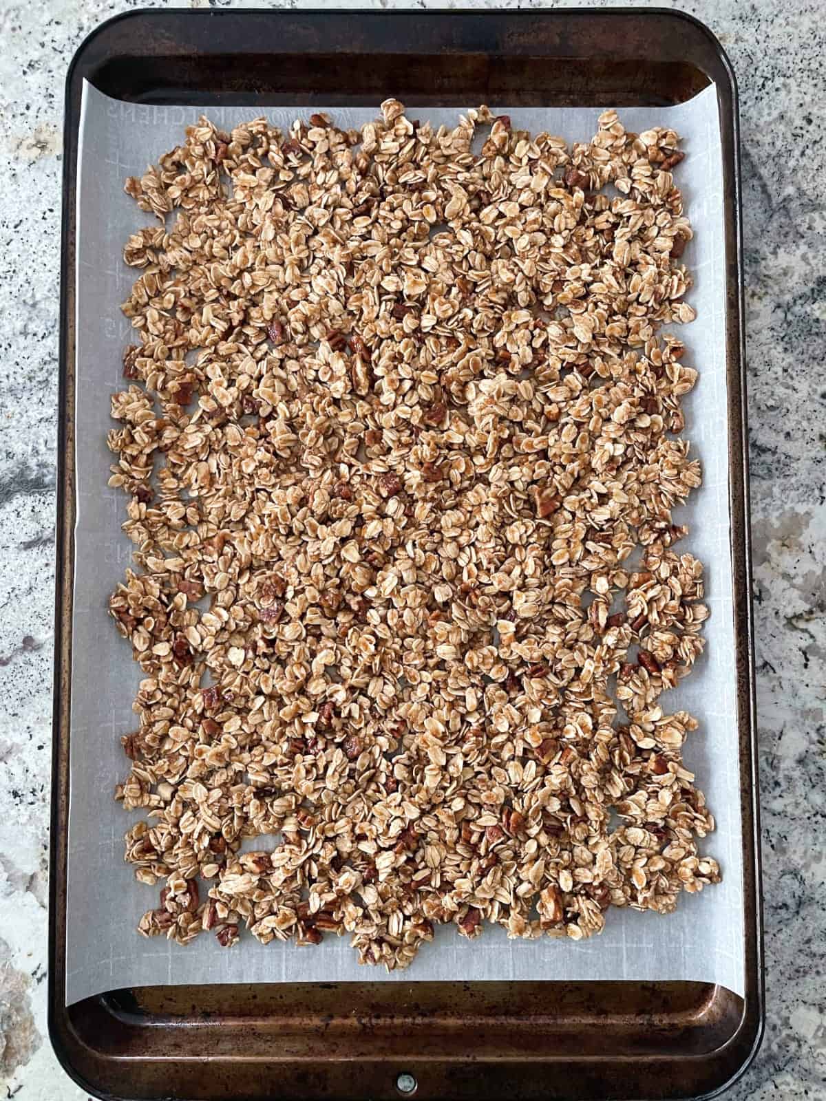 Unbaked granola on parchment-lined baking sheet.