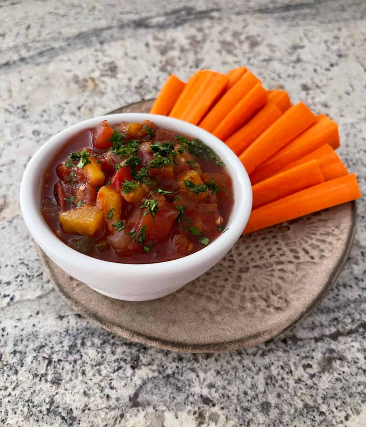 Slow cooked fresh peach salsa in small white serving bowl with carrot sticks.