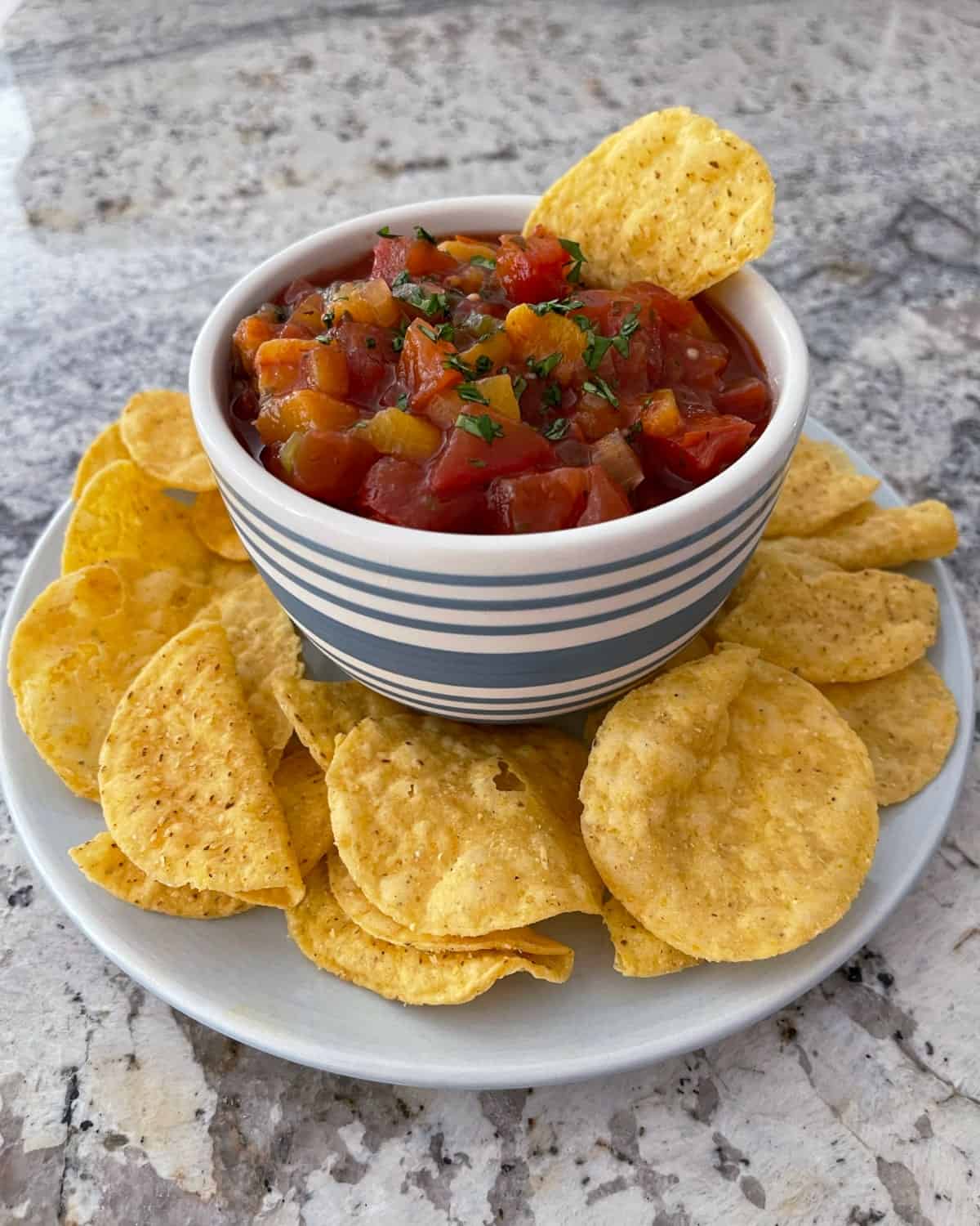 Slow cooker fresh peach salsa in small bowl with corn tortilla chips.