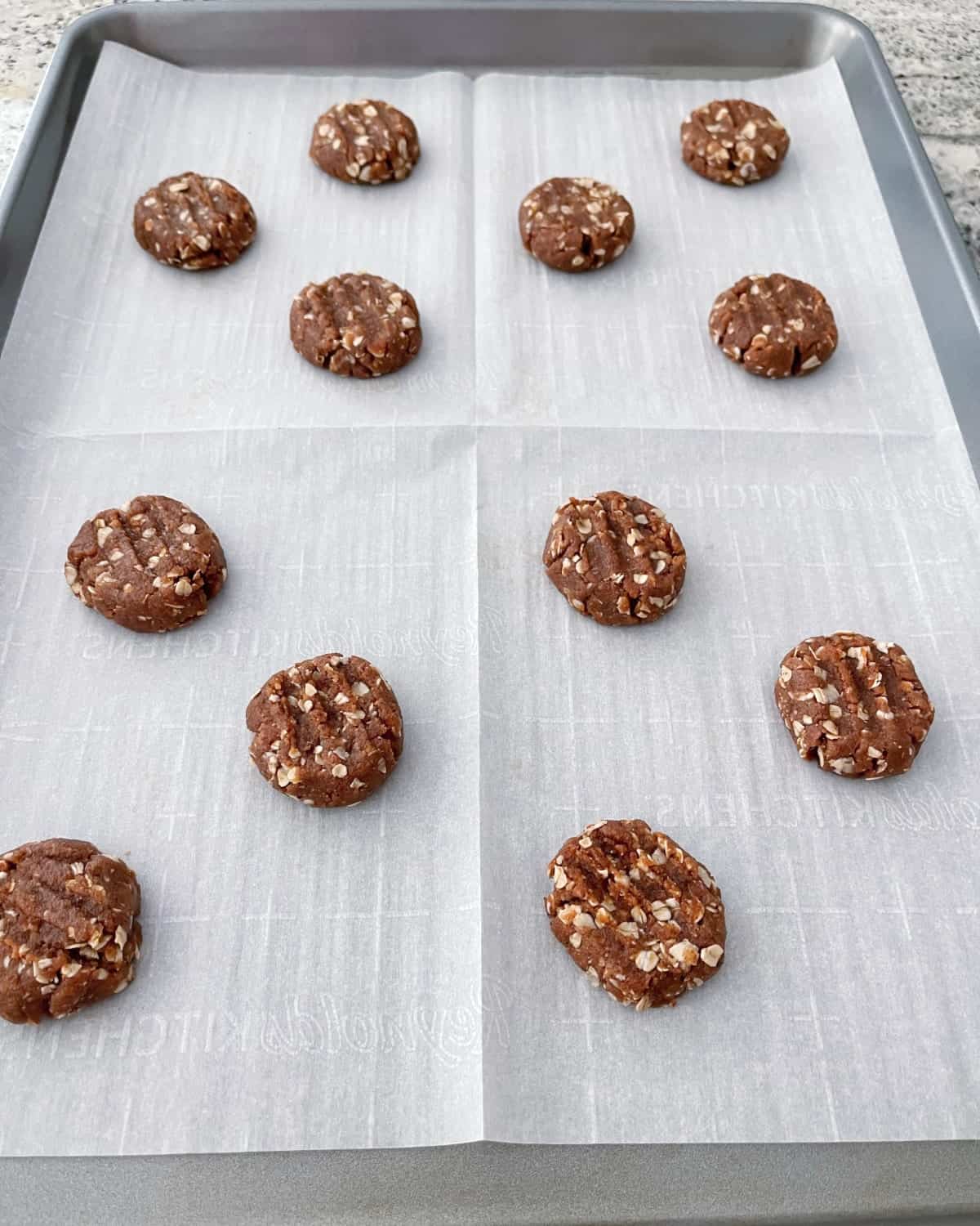 Unbaked coconut almond butter cookies on parchment-lined baking sheet.