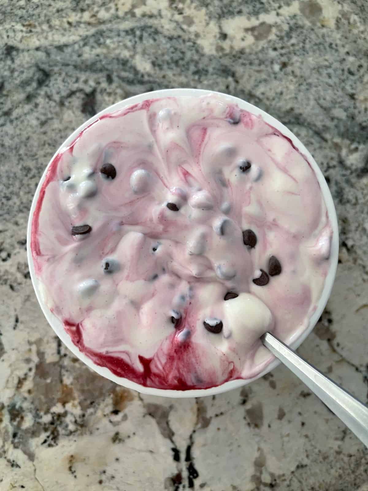 Unfrozen cherry chocolate chip cottage cheese ice cream in a cottage cheese container.