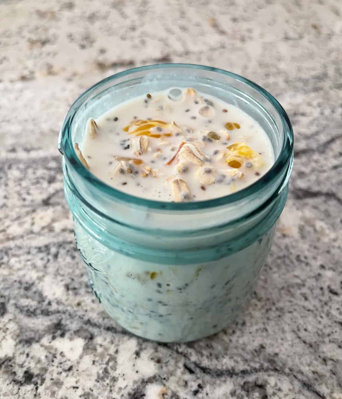 Combining chia orange overnight oats ingredients in small mason jar.