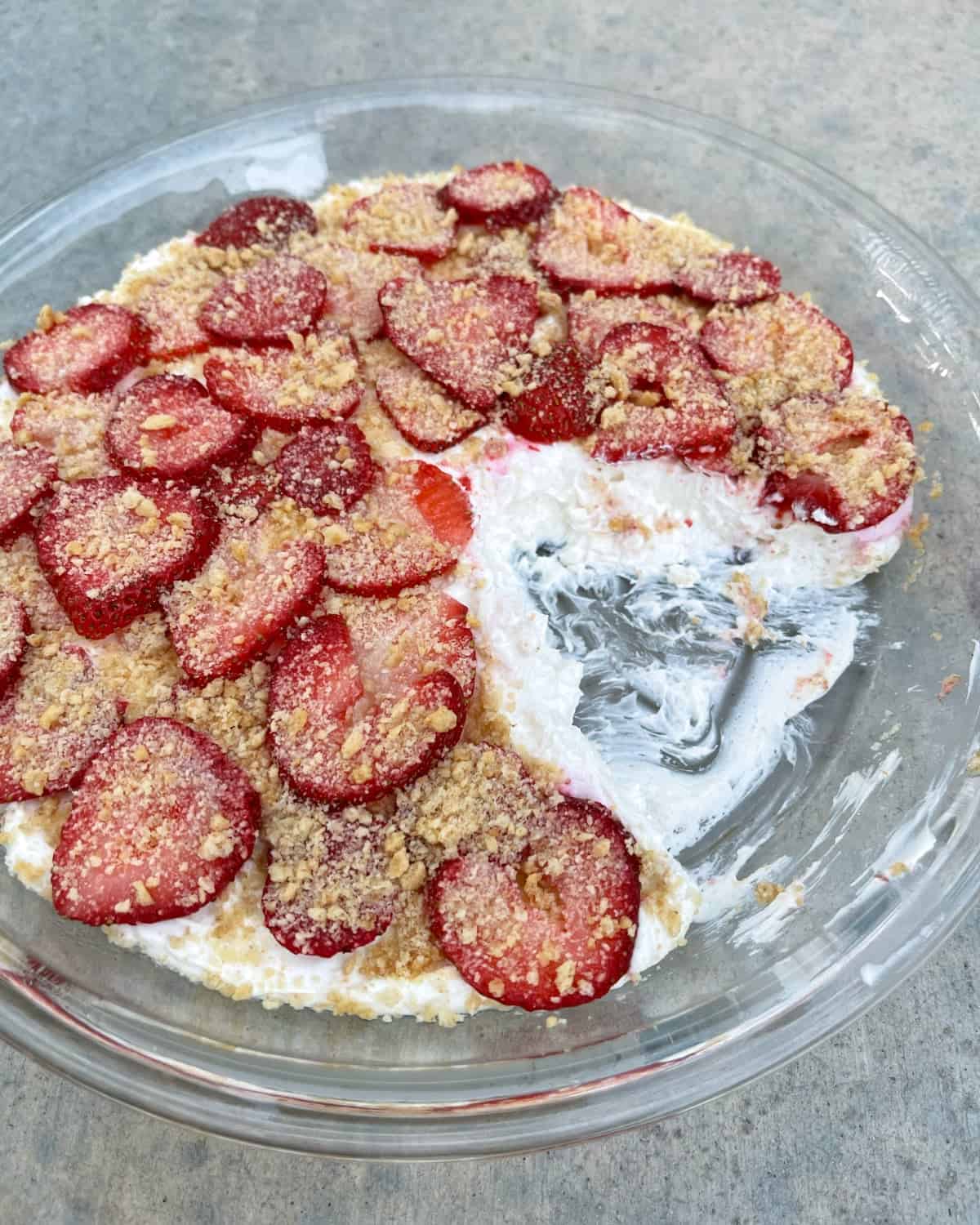 Serving no-bake strawberry cheesecake dessert from glass pie dish.