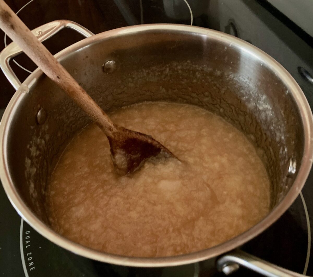 Stirring apple pear compote in pot with wooden spoon