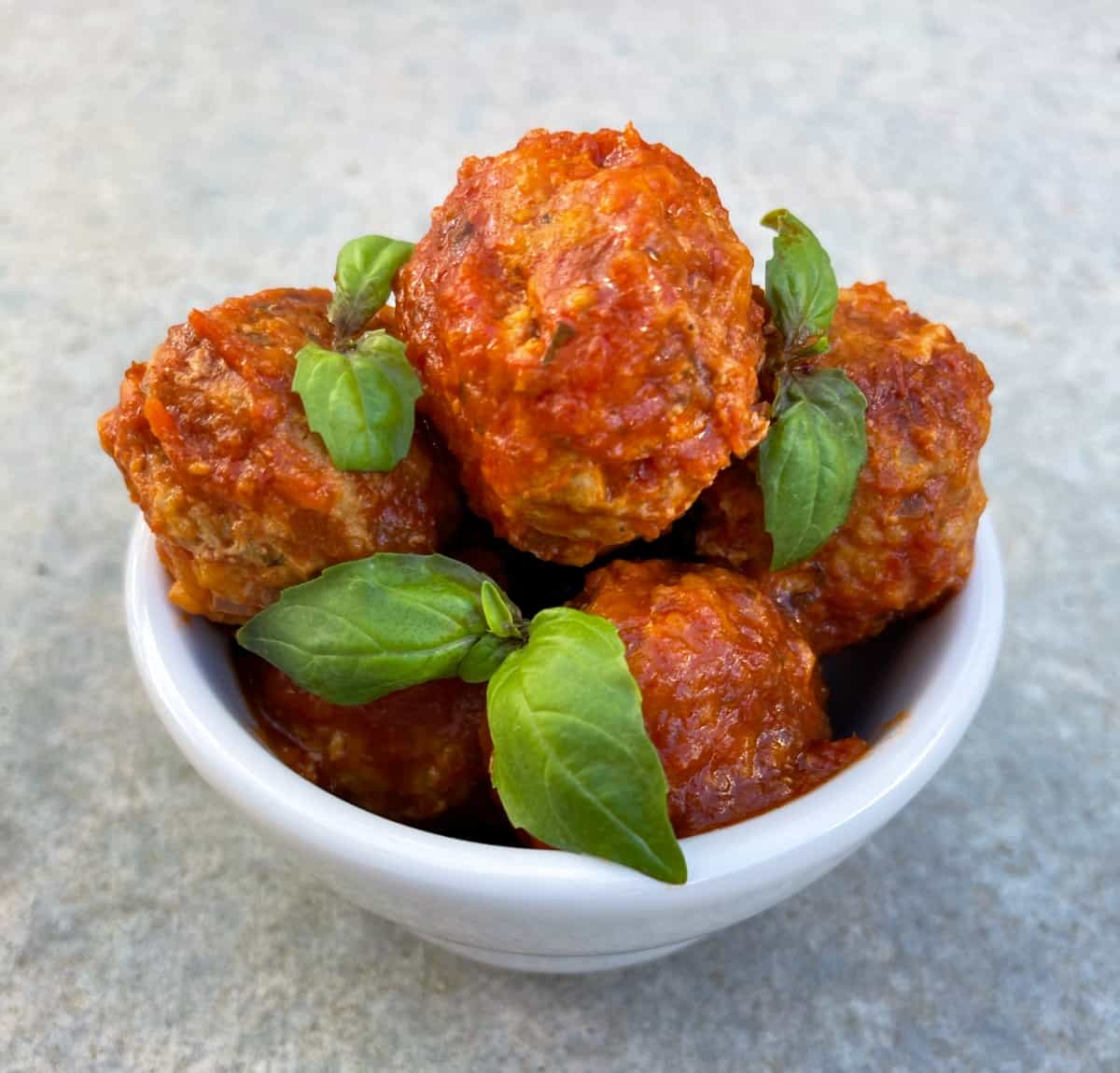 Italian Turkey Instant Pot Meatballs garnished with fresh basil in small white bowl.
