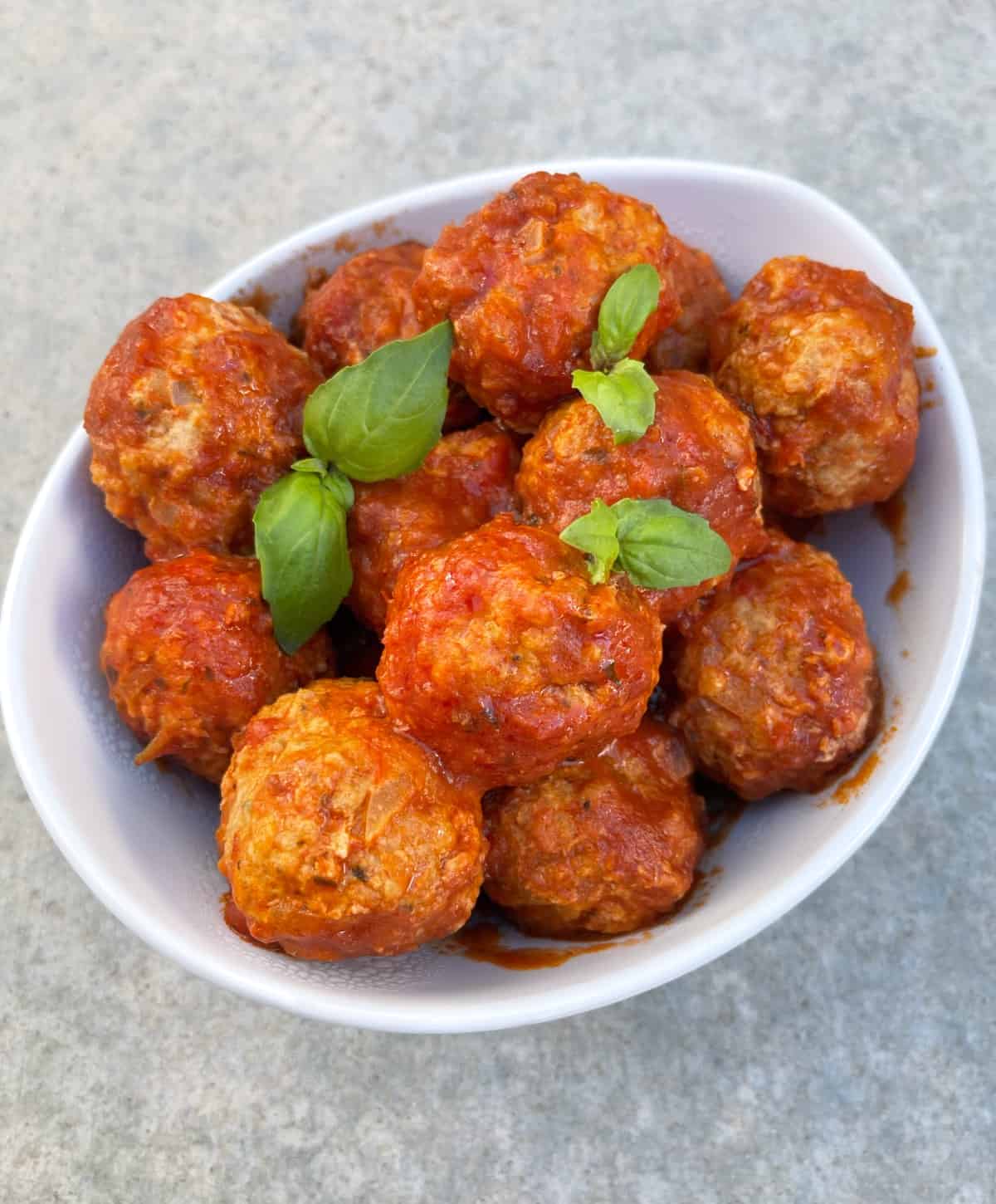 Fresh cooked Italian turkey Instant Pot meatballs topped with fresh basil in white serving dish.