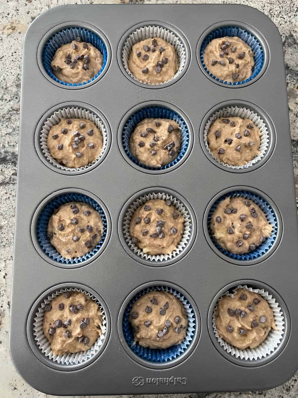 Unbaked banana chocolate chip pancake muffins in 12-cup muffin pan.