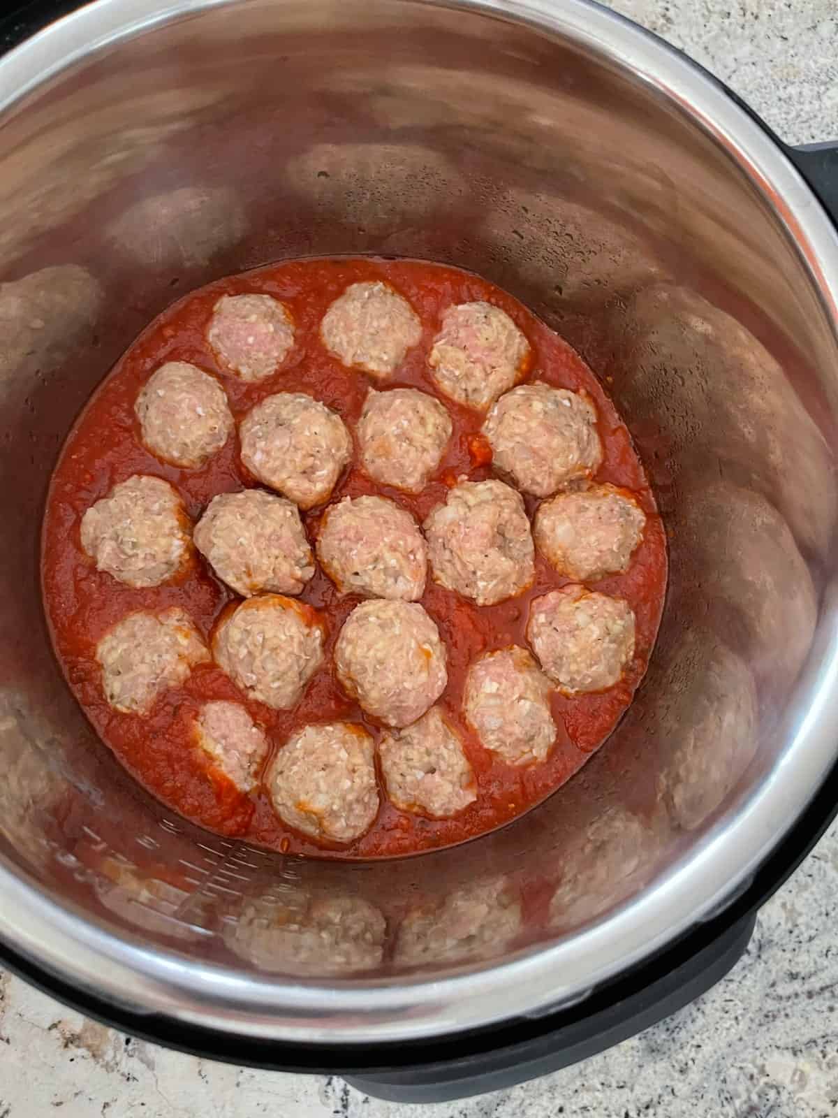 Twenty uncooked Italian turkey meatballs in marinara sauce in Instant Pot.