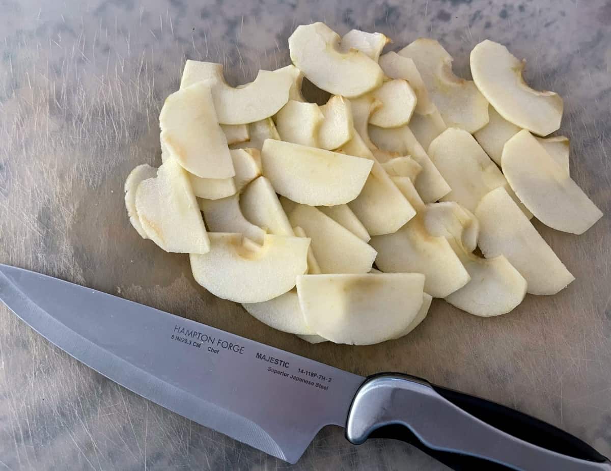 Fresh apple slices on cutting board with chef's knife.
