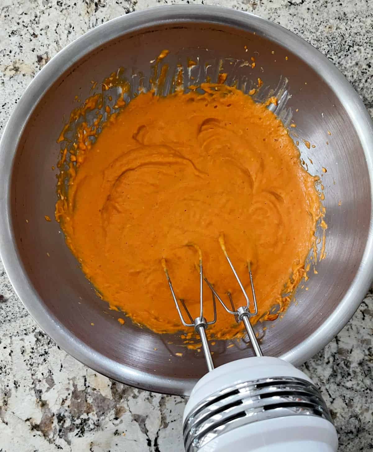 Beating light cream cheese, pure pumpkin puree, cornstarch and two eggs in stainless bowl with hand mixer.
