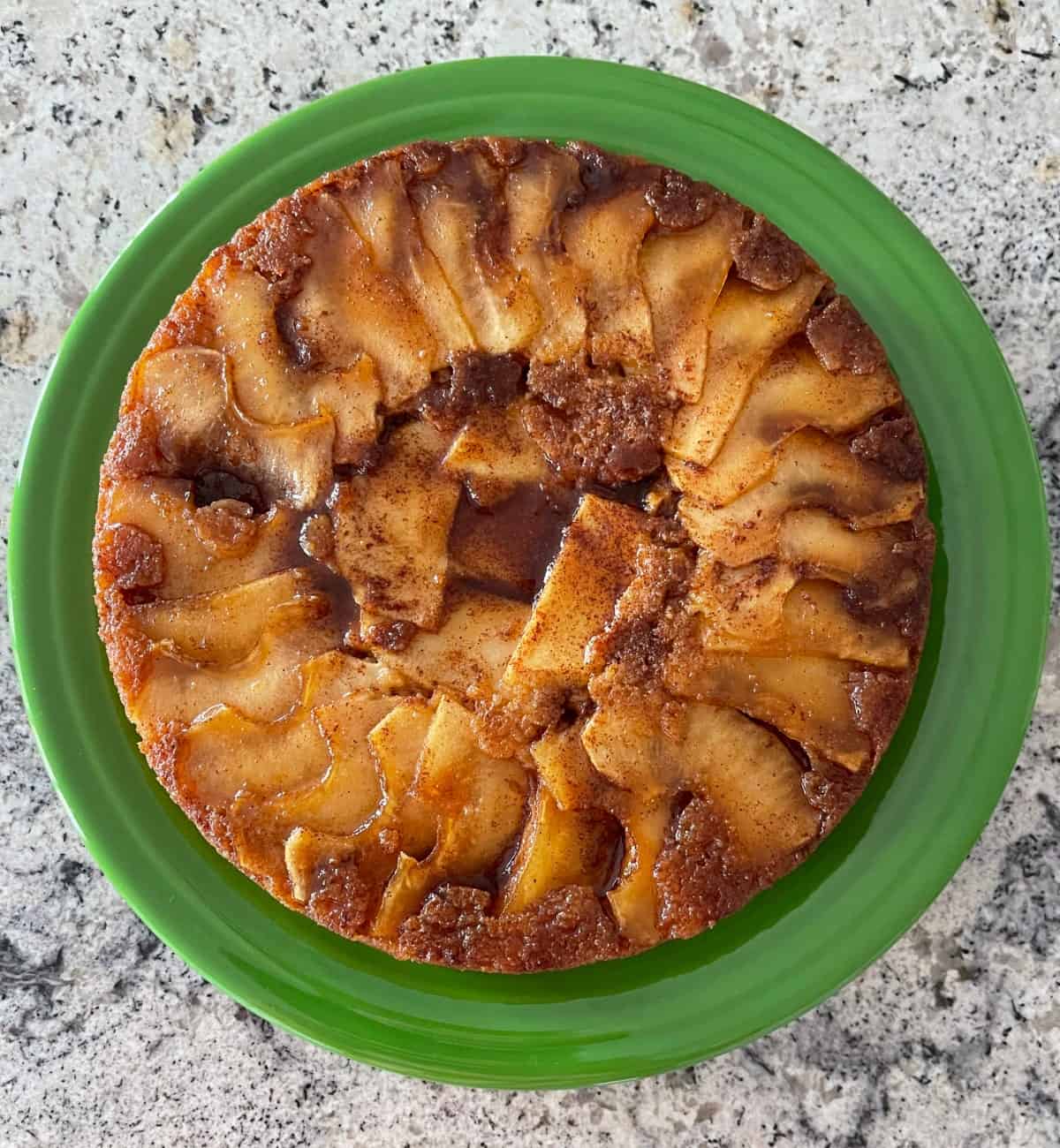 Fresh baked cinnamon apple quick cake on large green serving plate.