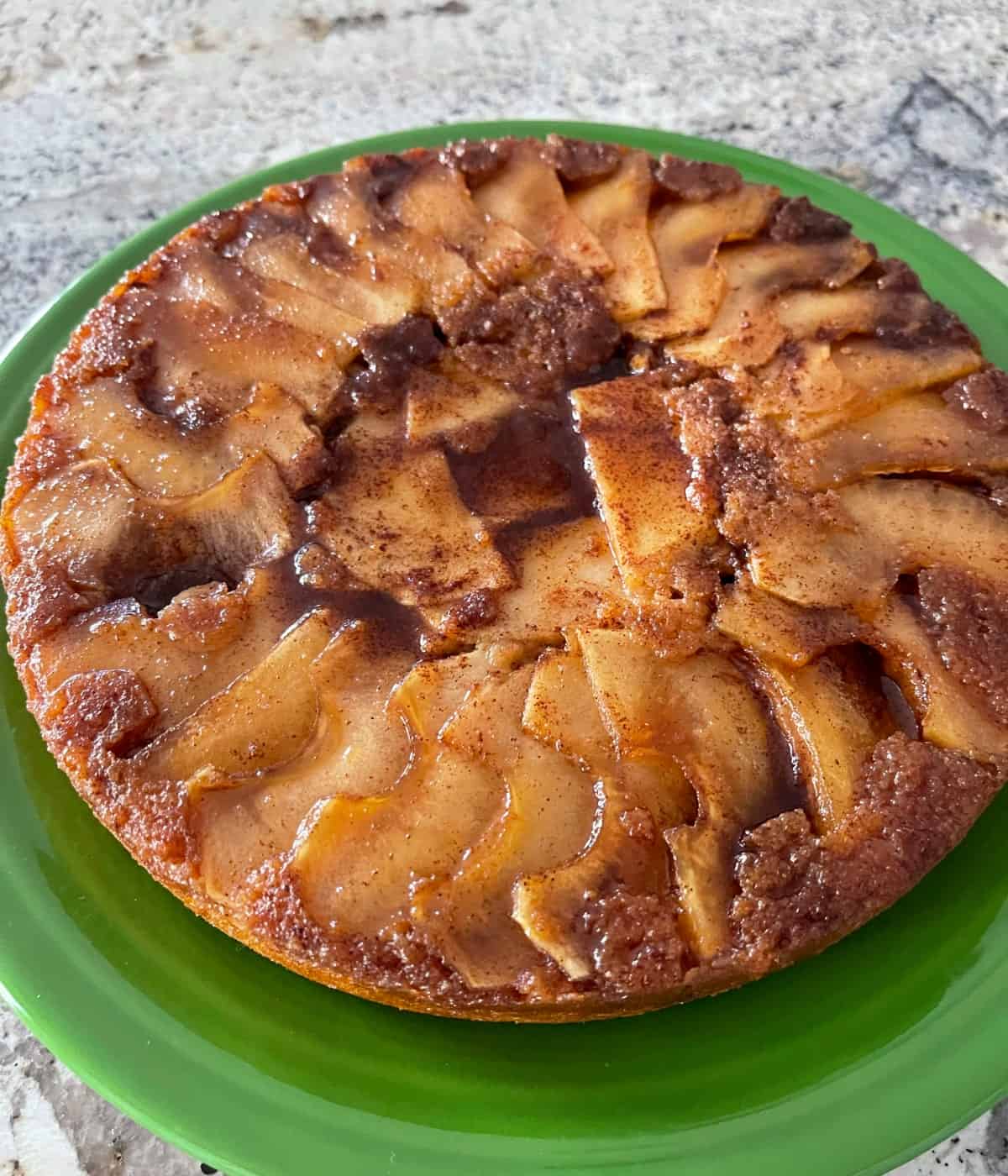 Fresh baked cinnamon apple cake on green serving platter.