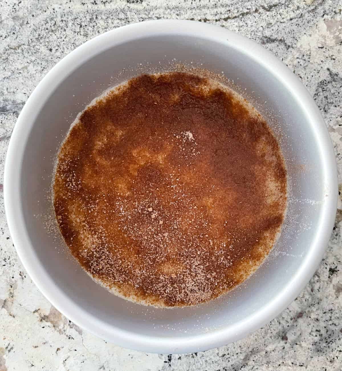 Round cake pan with melted butter, Truvia Brown Sugar, Truvia Baking Blend and cinnamon on granite.
