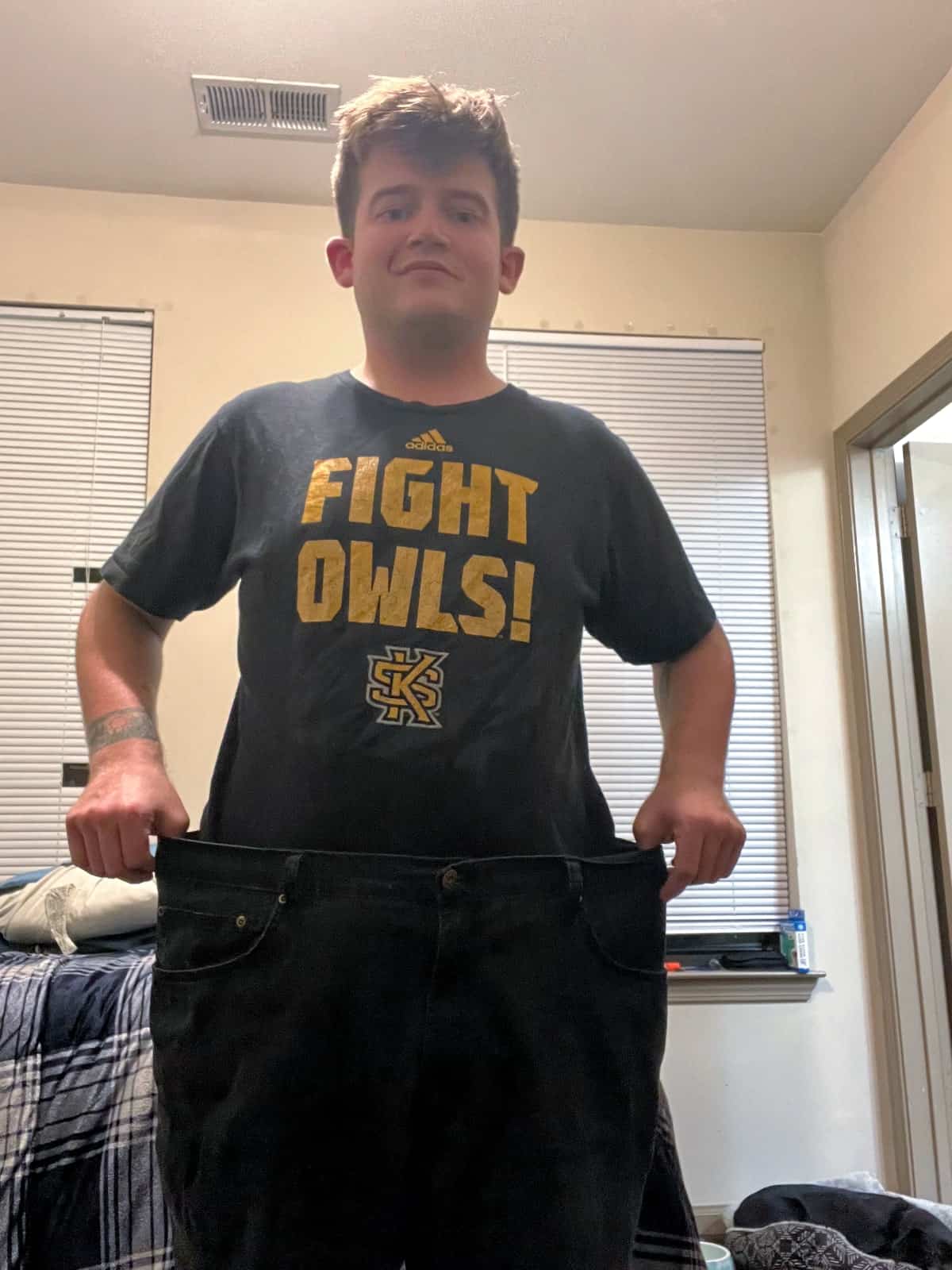 Matthew wearing pants that are now too large due to weight loss.