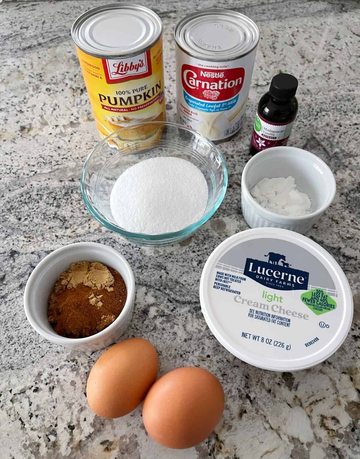 Ingredients including can of pure pumpkin, low-fat evaporated milk, vanilla extract, cornstarch, Truvia Baking Blend, brown sugar with cinnamon, light cream cheese and two eggs on granite.