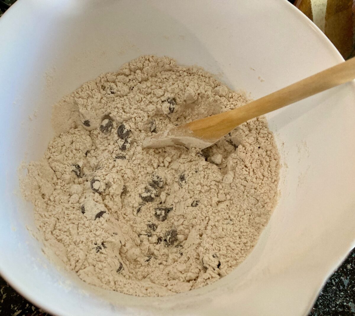 Mixing gingerbread dry ingredients in mixing bowl with wooden spoon.