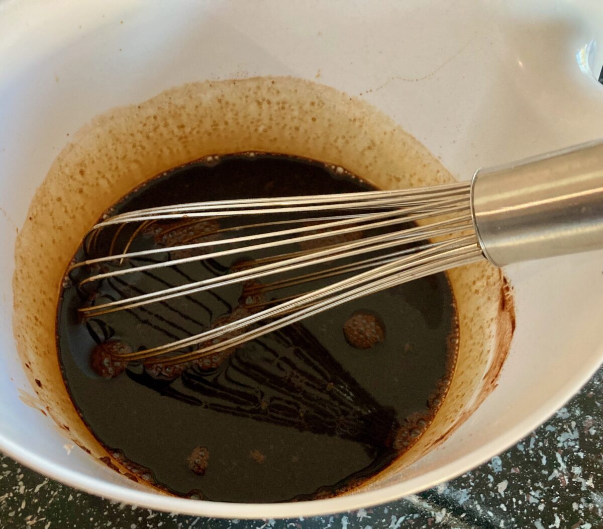 Whisking molasses, boiling water, brown sugar, cocoa, egg and oil in mixing bowl.