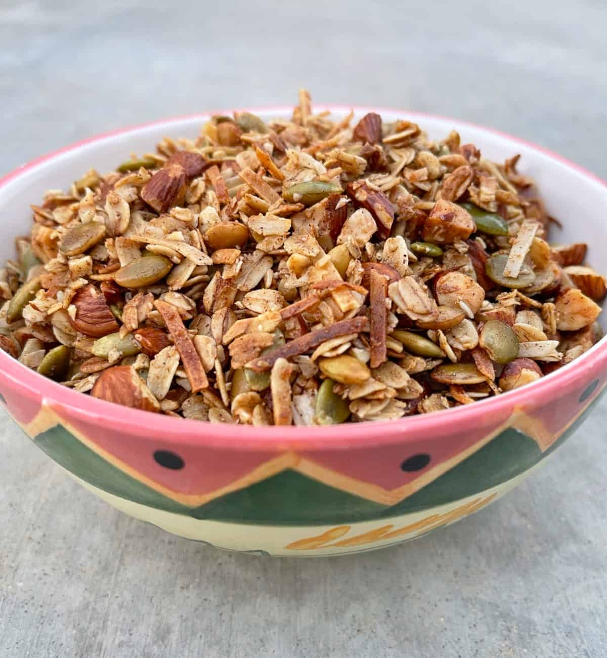Fresh cooked air fryer toasted oat granola in a small, colorful painted bowl.