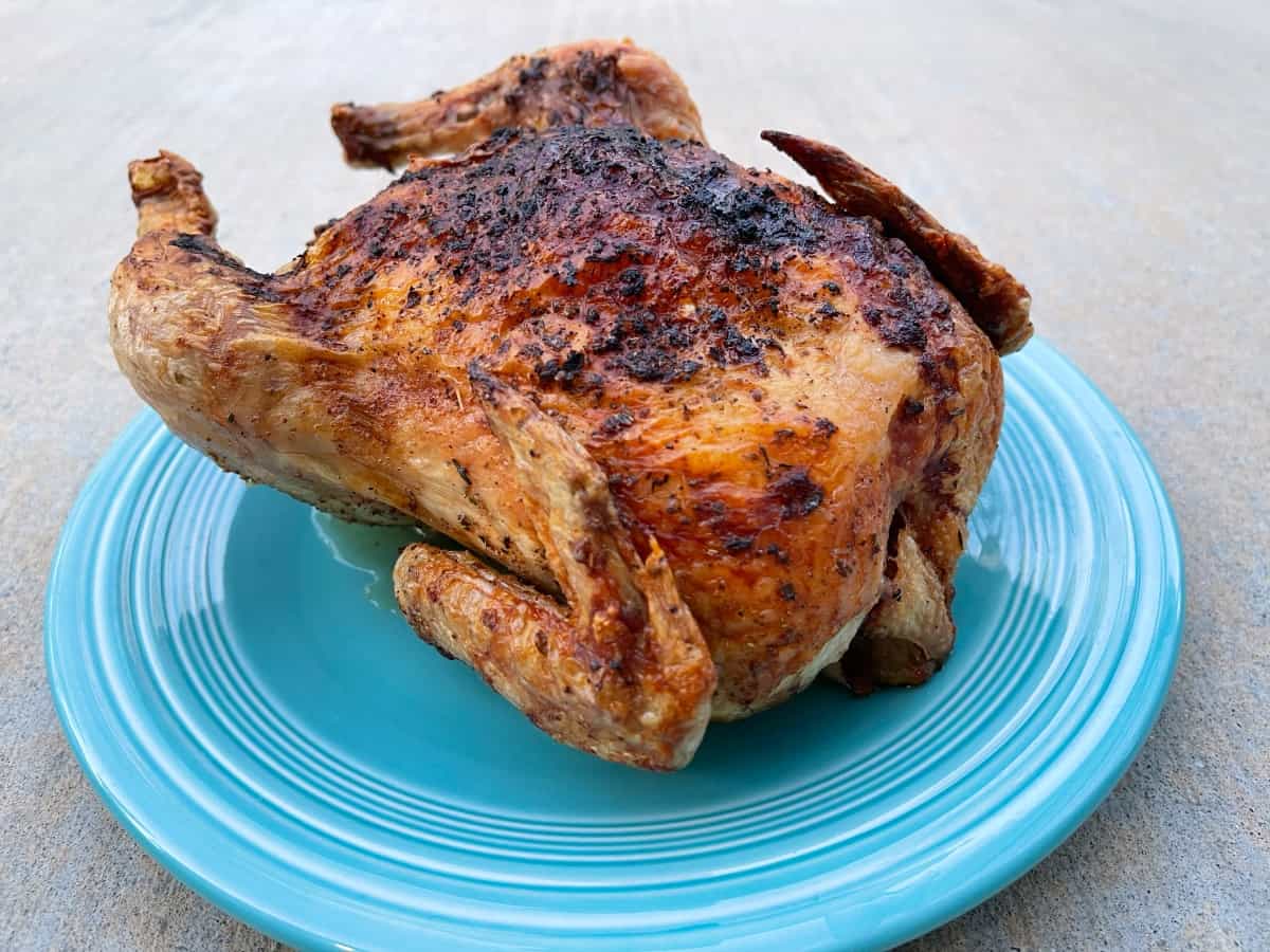 Fresh roasted air fryer whole chicken on green serving platter.