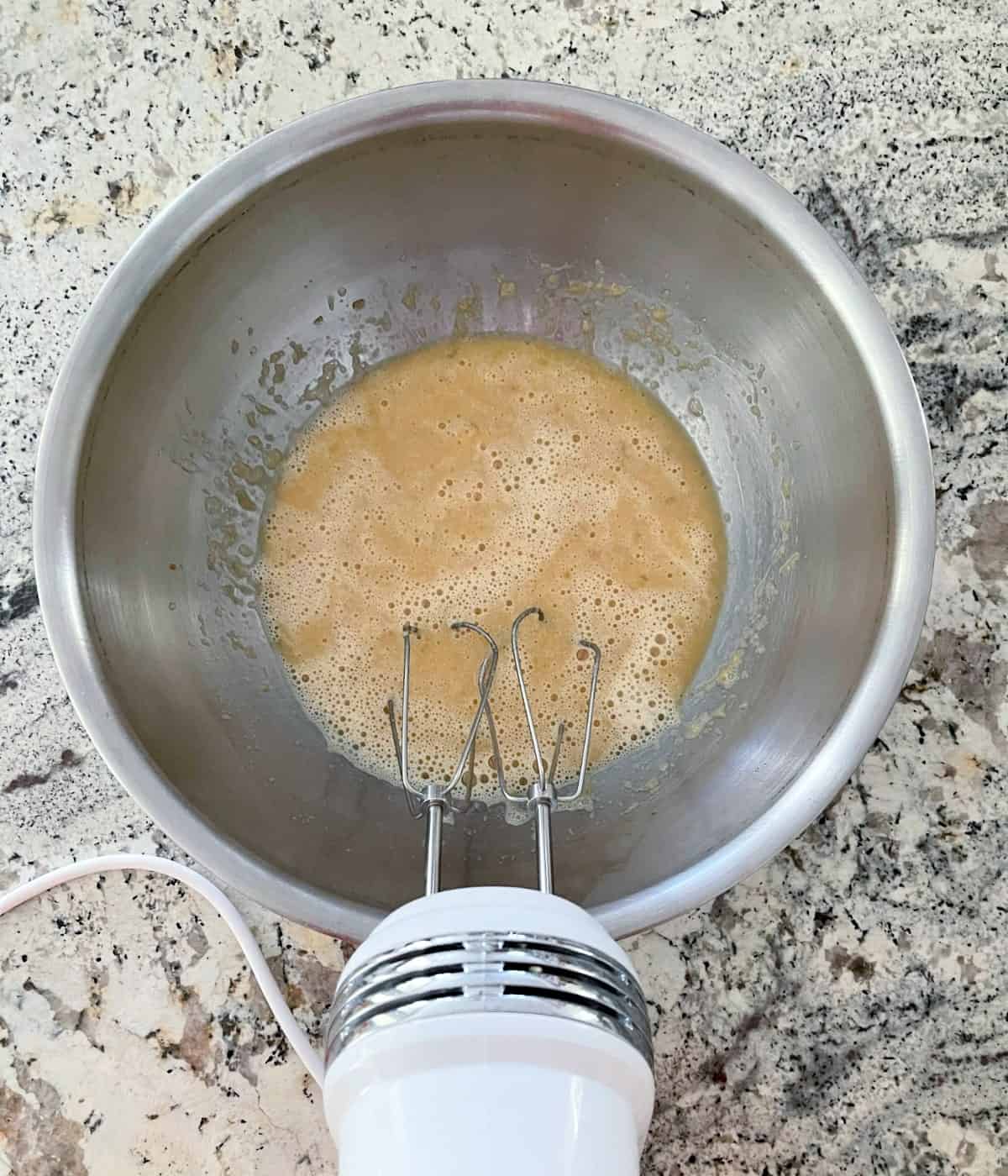 Beating banana, Truvia brown sugar blend, two eggs, unsweetened applesauce and vanilla extract in mixing bowl with handheld electric mixer.