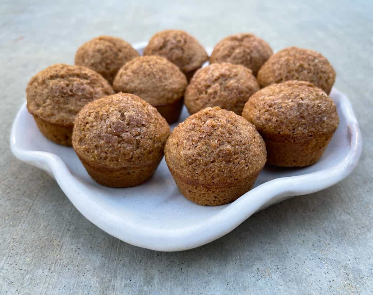 Mini cinnamon apple muffins on white wavy ceramic plate.