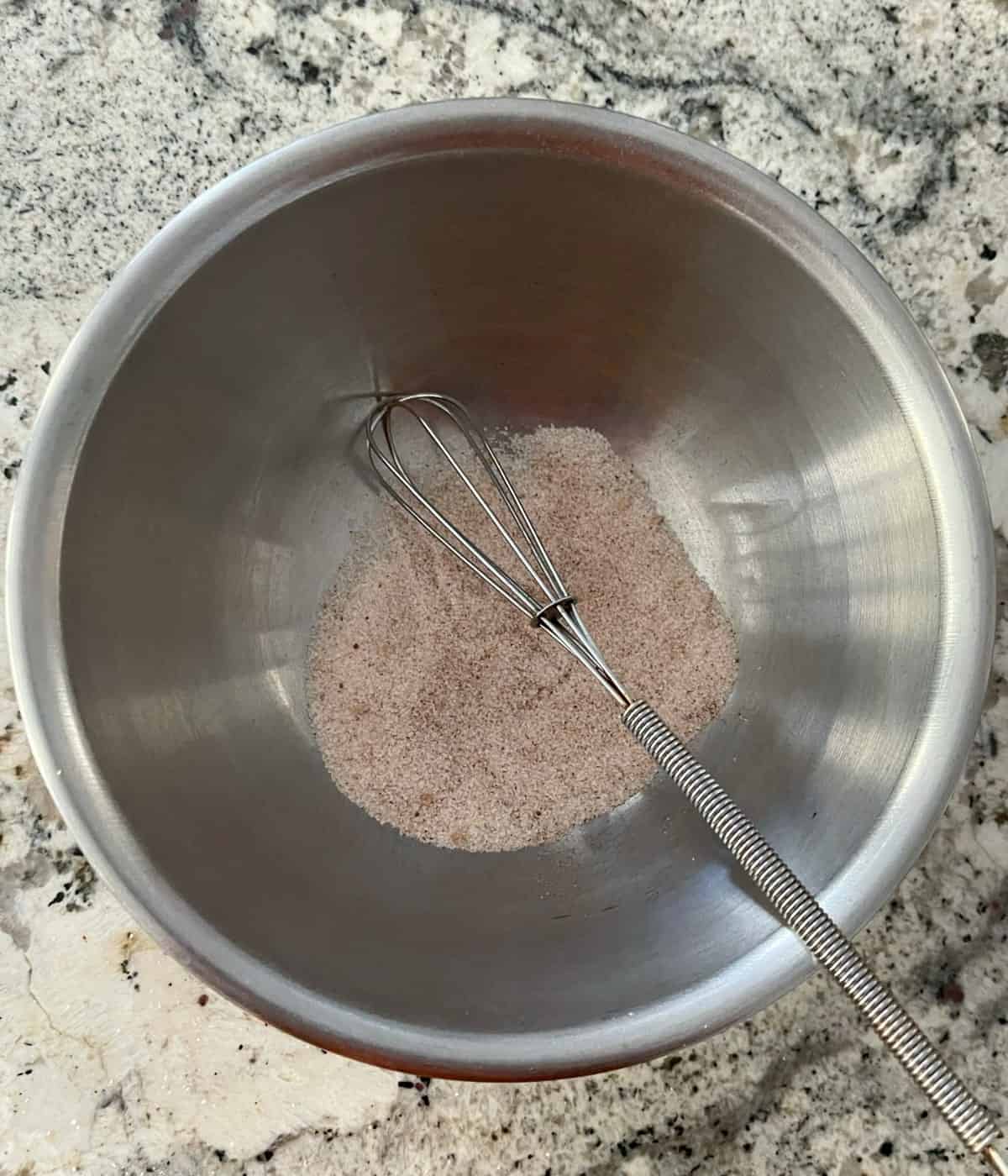 Cinnamon-sugar mixture in small bowl with whisk.