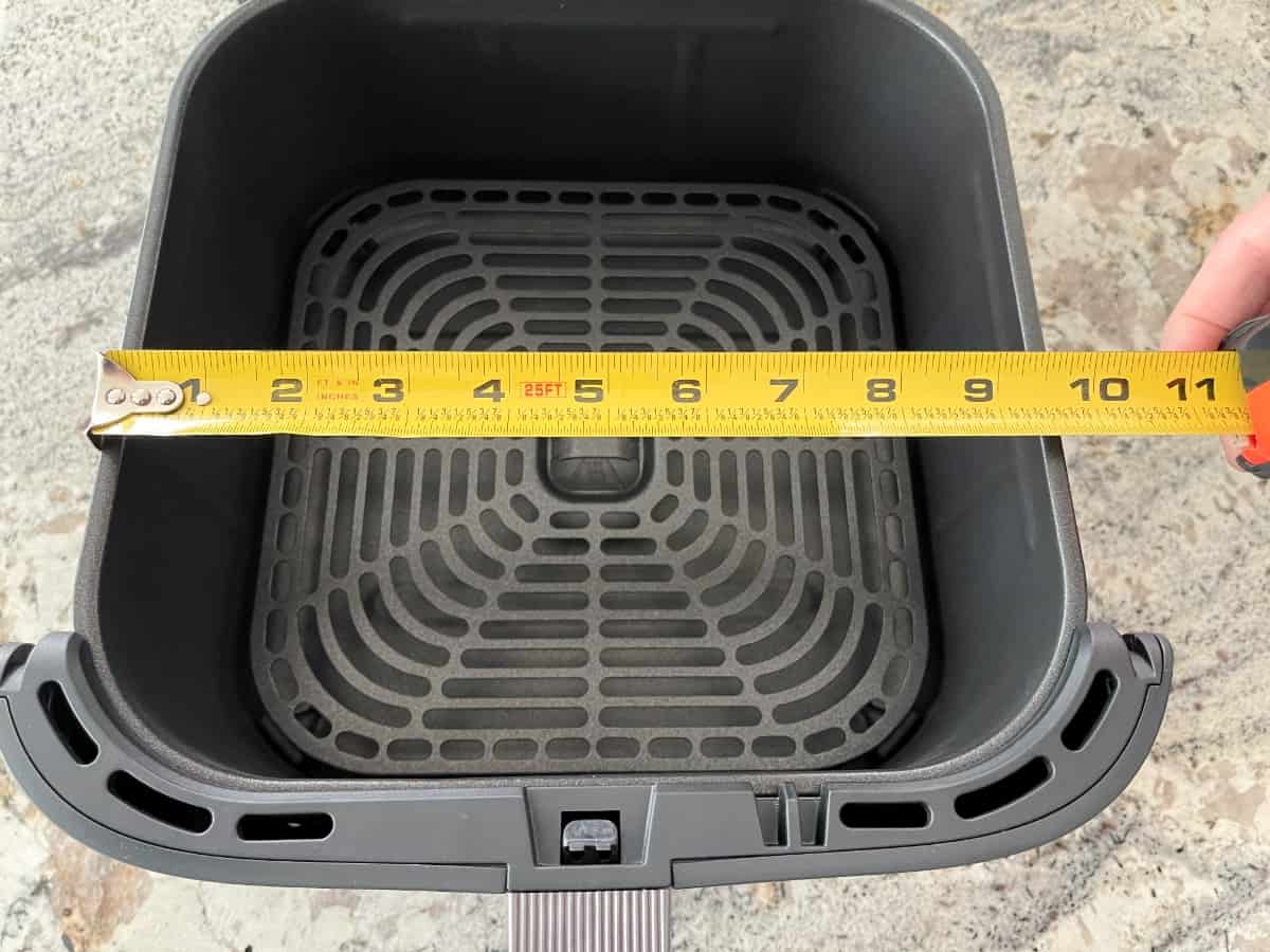 Measuring the Cosori TurboBlaze air fryer basket with a measuring tape in inches.