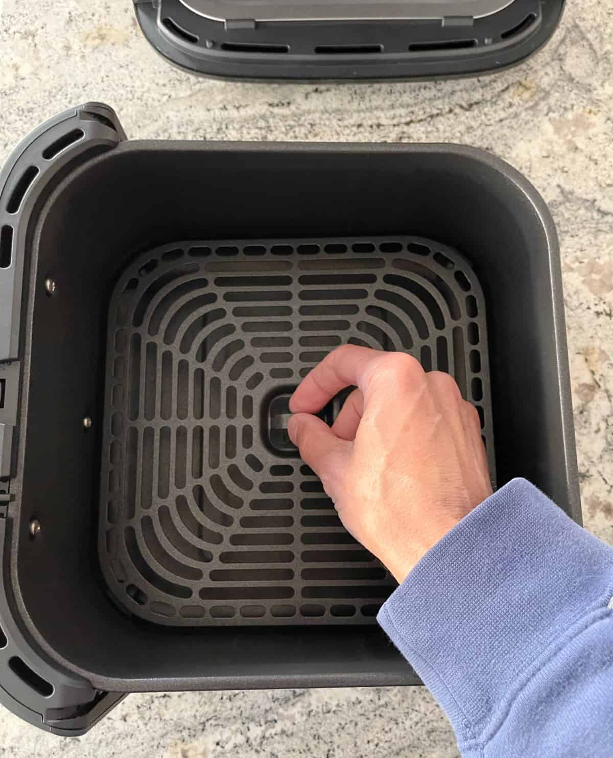 Inserting Cosori air fryer crisper tray into basket.