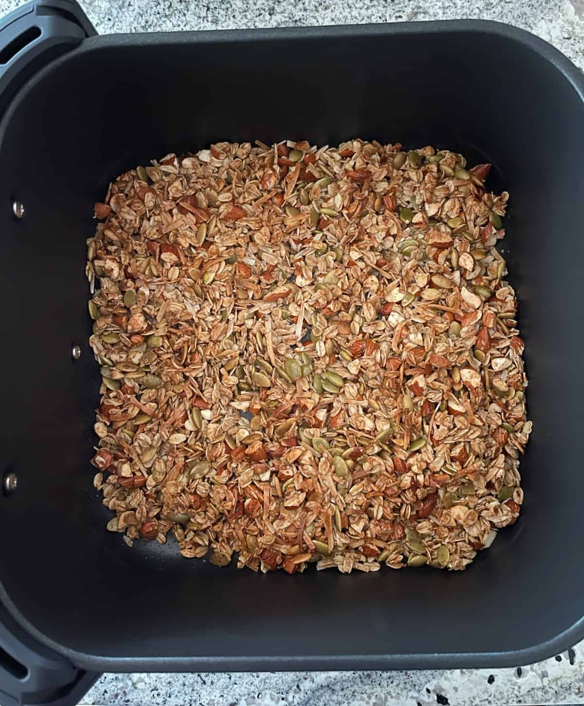 Fresh cooked toasted oat granola cooling in air fryer basket.
