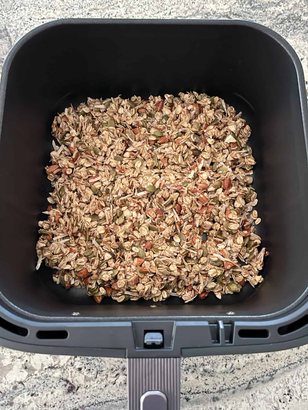 Uncooked air fryer granola in preheated cooking basket.