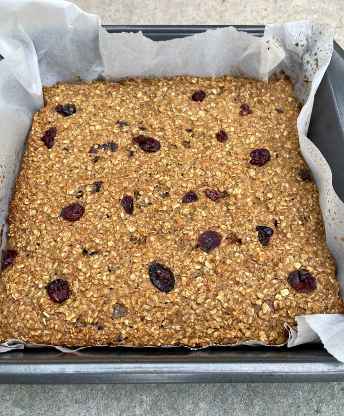 Cranberry ginger baked oatmeal in parchment lined baking pan.