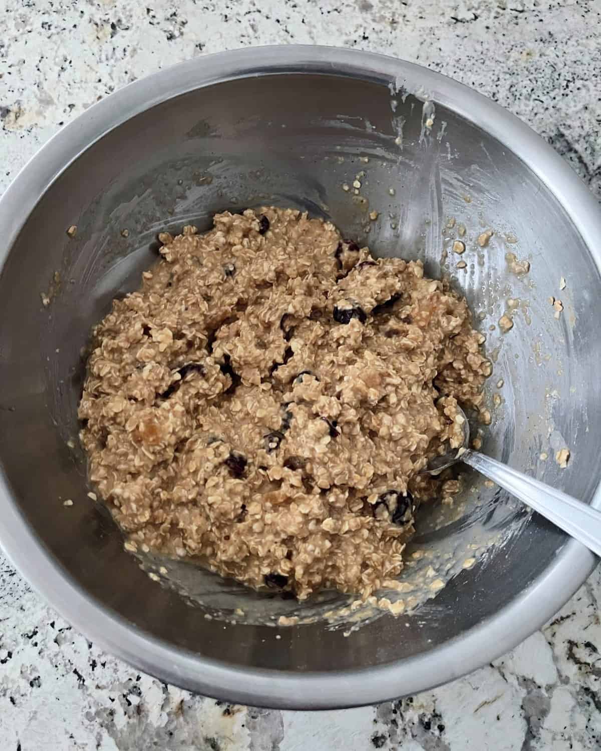 Stirring cranberry ginger oatmeal bar batter in mixing bowl with a spoon.