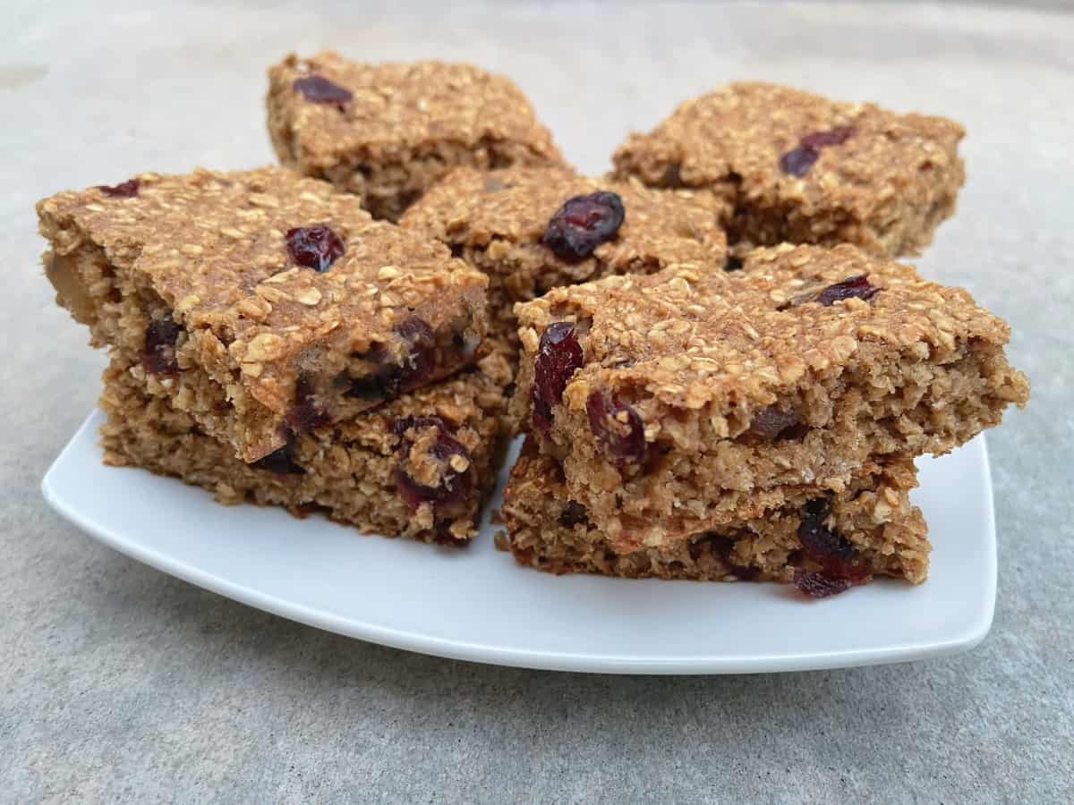 Cranberry ginger oatmeal bars stacked two high on small white plate.